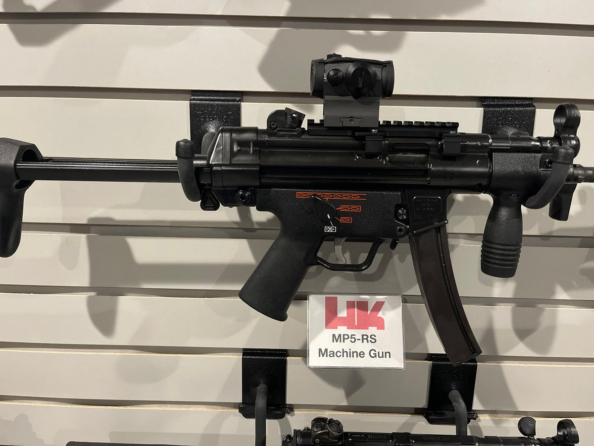 Black machine gun displayed on a wall with a visible brand label.