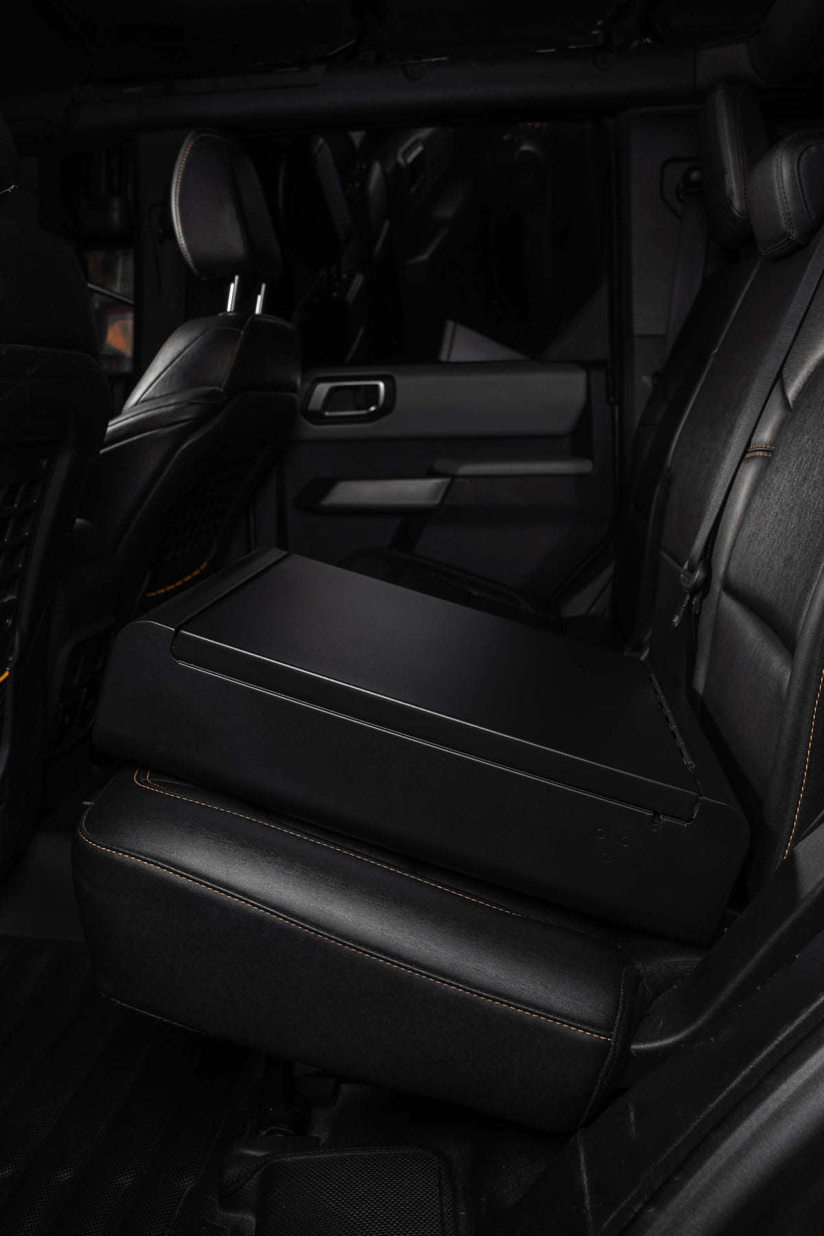 Black leather interior of a vehicle with a focus on the back seat.