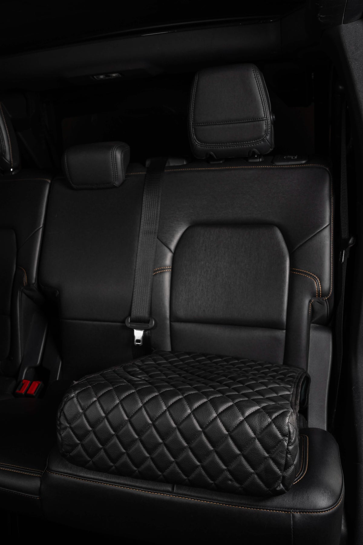 Black quilted car seat cover on a car seat with a dark interior.