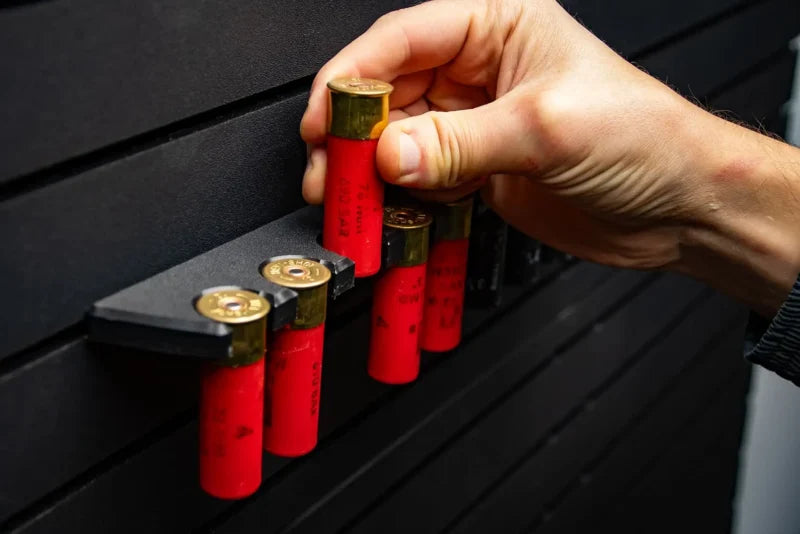 Hand arranging red shotgun shells on a black surface