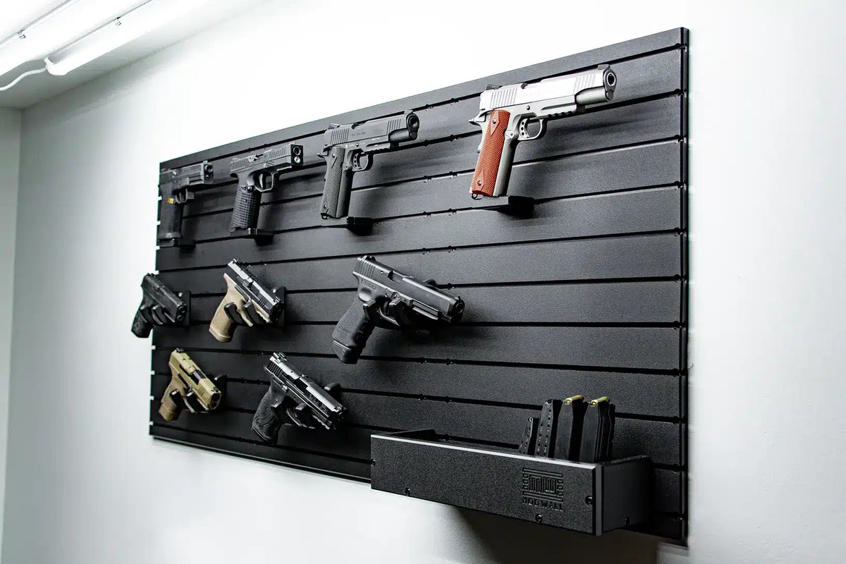 Wall-mounted gun rack with various firearms displayed on a gray slat wall.