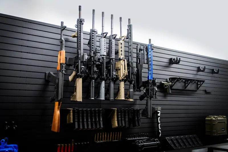 Wall-mounted gun rack with various firearms and accessories in a storage room.
