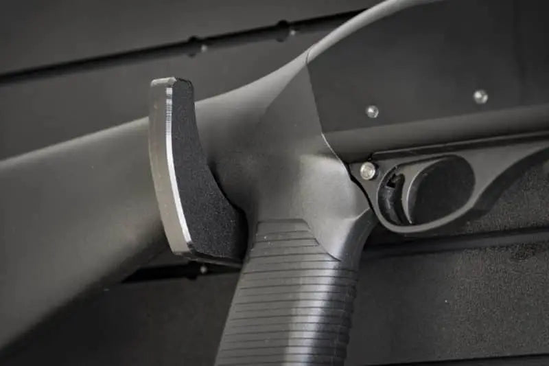 Close-up of a black firearm with a focus on the trigger and grip.