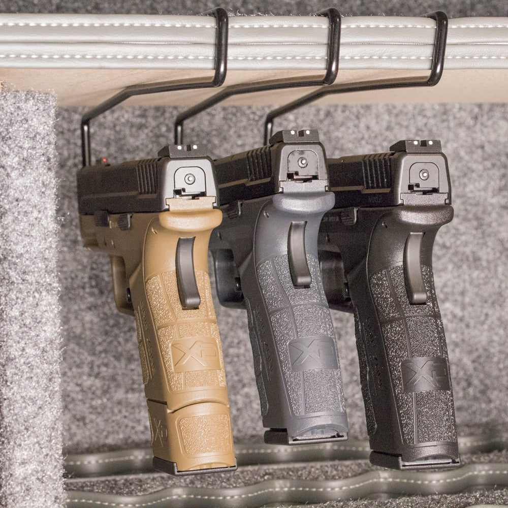 Three gun grips in different colors on a textured surface