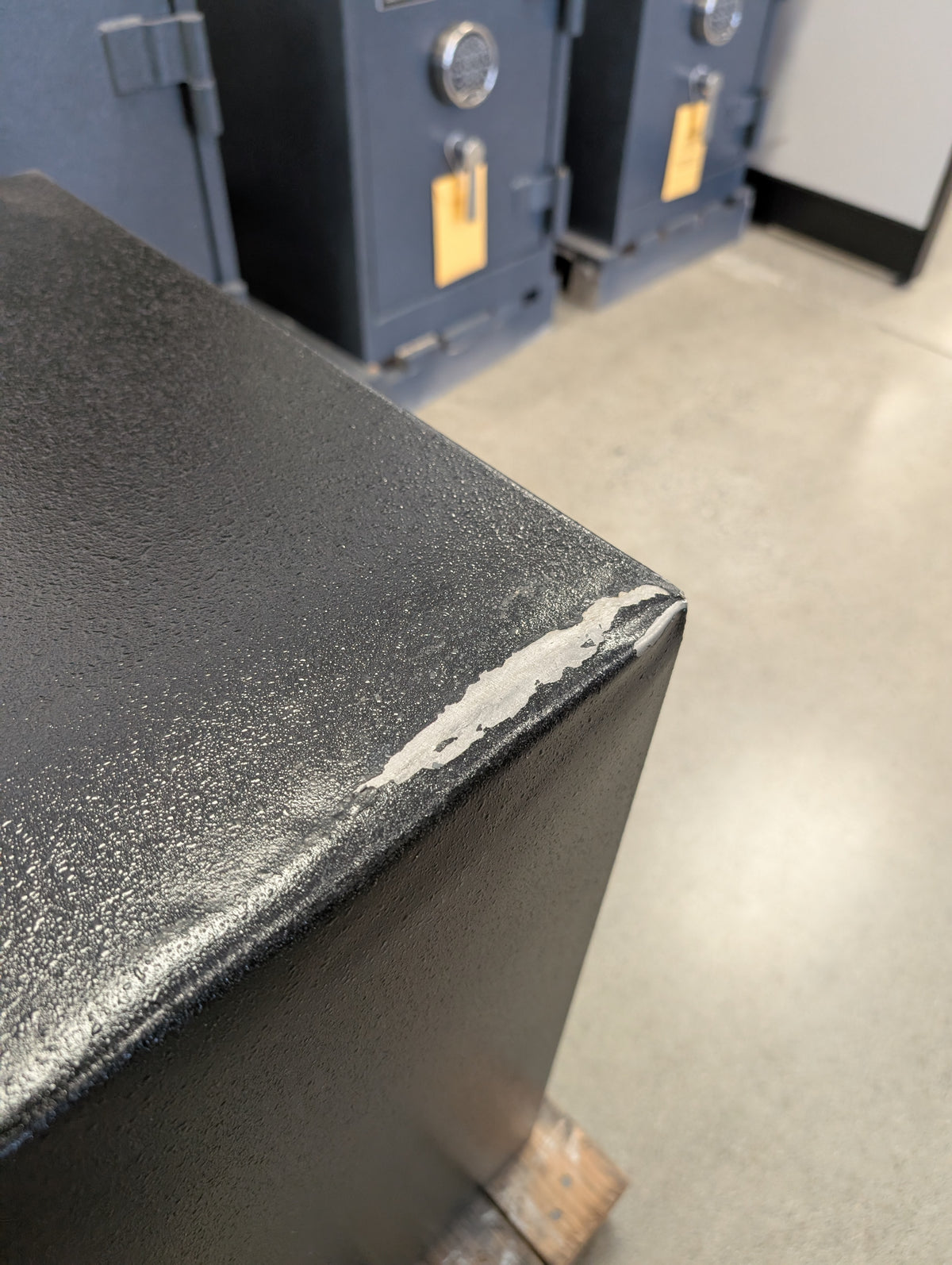 Close-up view of the top back right corner. It has a bump, scratch and some chipped paint. 