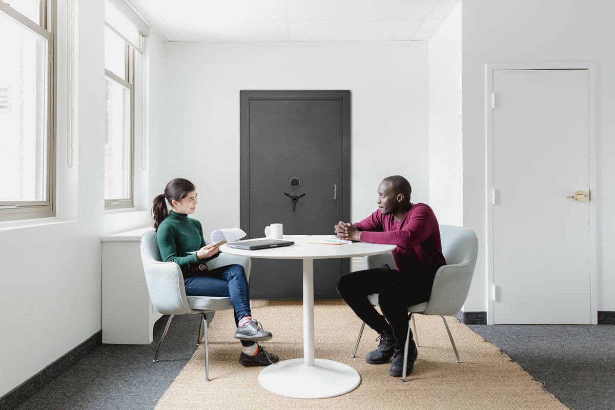 Two people sitting at a table with the Vulcan Vault door displayed behind them. 