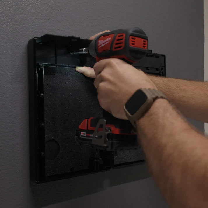 Person using a Milwaukee tool on a wall-mounted device