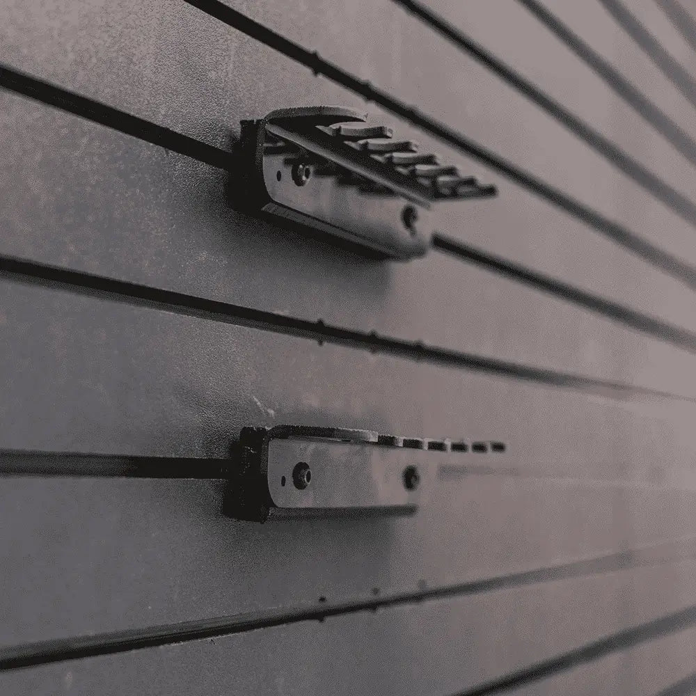 Close-up of two black metal brackets on a gray slat wall.