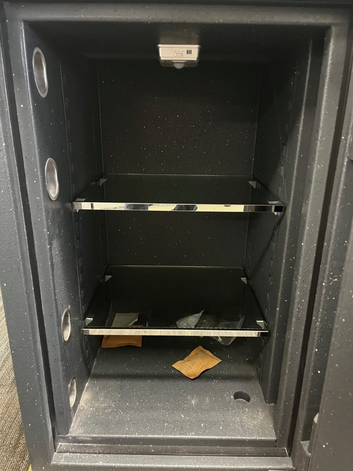 Close-up view of the inside of the safe. It comes with two glass shelves. The shelves are adjustable. It also had a light on the top inside of the safe. The light is battery operated. 